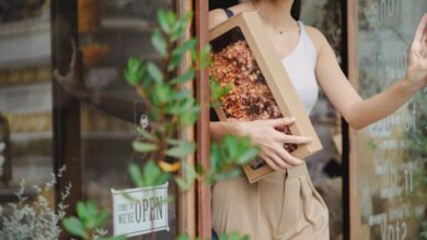 Gift - A young woman happily exits a shop holding a box of dried flowers.