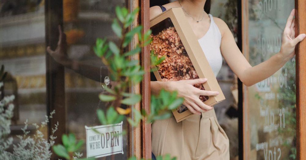 Gift - A young woman happily exits a shop holding a box of dried flowers.