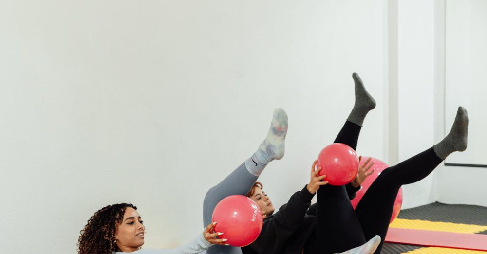 Foam Mats - Two women engaging in a fitness routine with pink exercise balls at a modern gym.