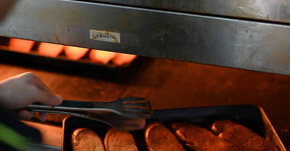 Toasters - A baker removes freshly toasted bread slices from the oven, showcasing baking in progress.