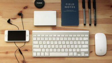 Gadgets - Top view of a modern desk setup featuring electronics, stationery, and gadgets on a wooden surface.