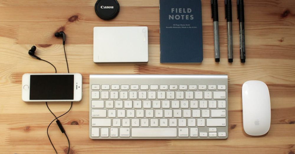 Gadgets - Top view of a modern desk setup featuring electronics, stationery, and gadgets on a wooden surface.