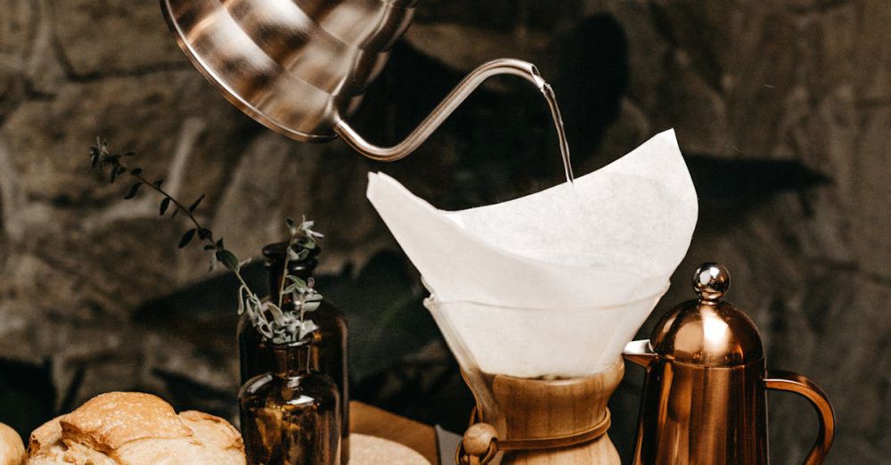 Bread Makers - Hand pouring coffee into a Chemex surrounded by fresh cherries and breakfast items indoors.