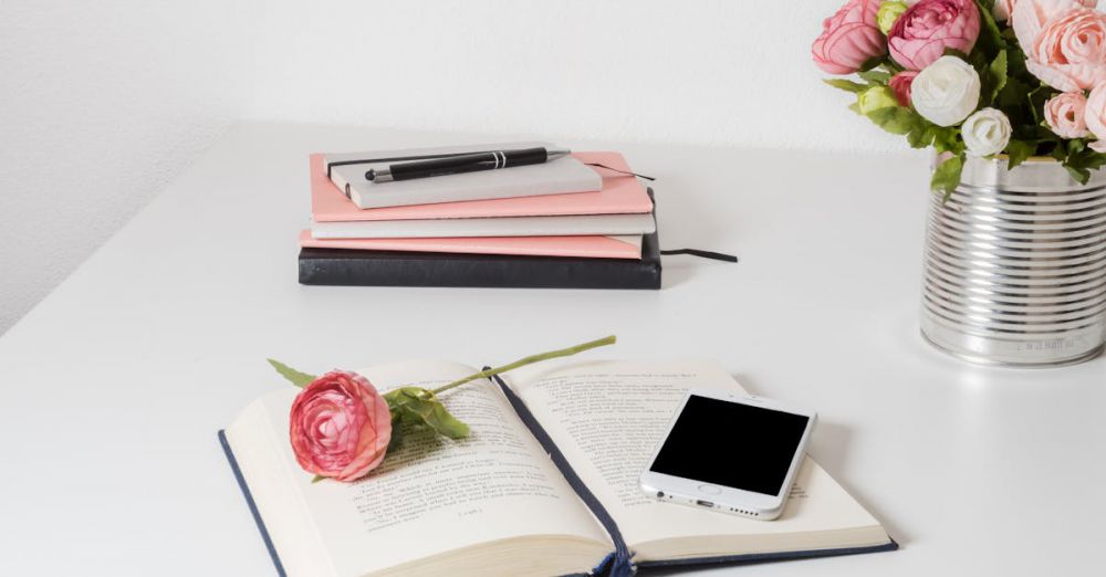 Can Openers - A stylish home office setup with open book, smartphone, and flowers on a white desk.