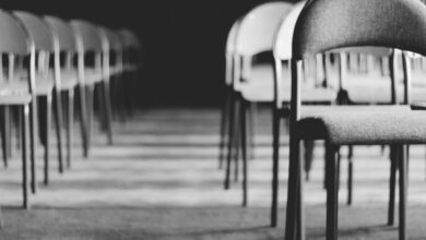 Chairs - Row of empty chairs in a dimly lit hall, captured in black and white.