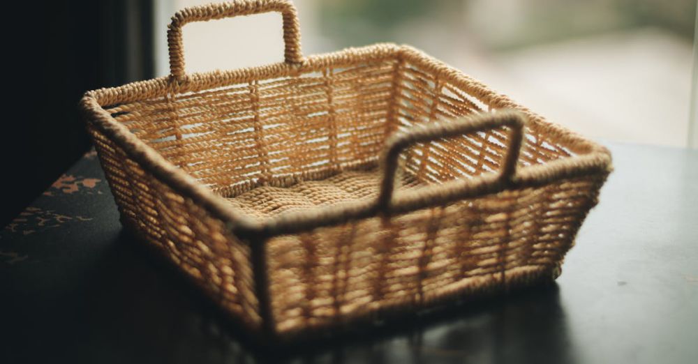 Basket - A close-up of a handmade wicker basket with handles, showcasing intricate weaving indoors.