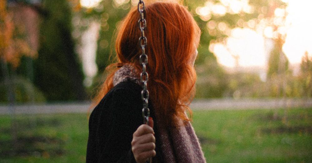 Swing Sets - A woman with red hair on a swing in a serene autumn park setting.