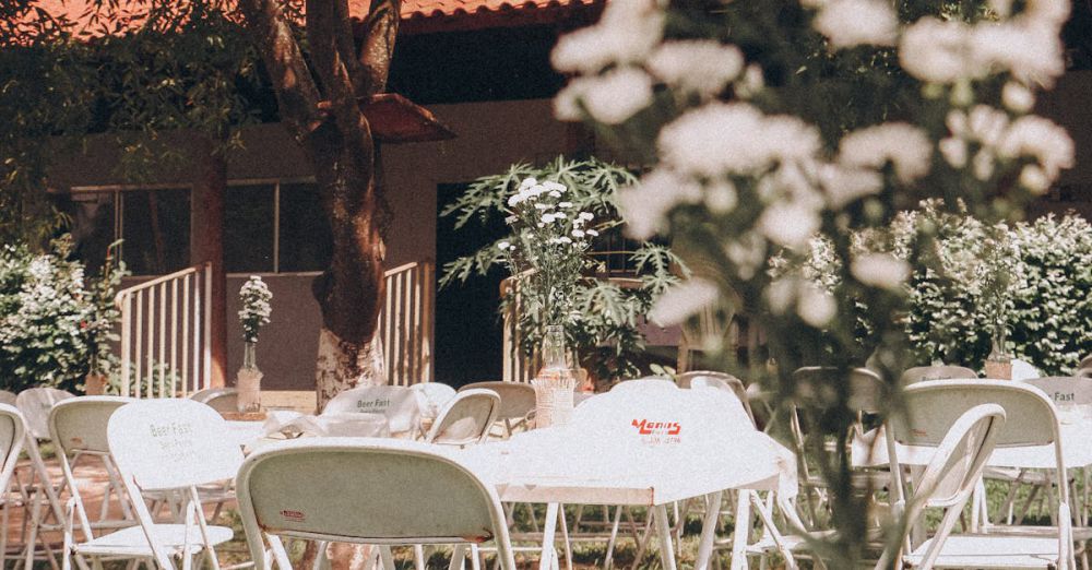 Folding Chairs - Sunny garden event setup with white chairs and floral arrangements.