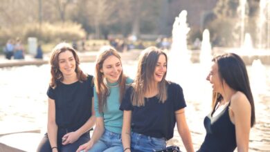 Fountains - Four friends laughing and chatting outdoors by a water fountain on a sunny day.