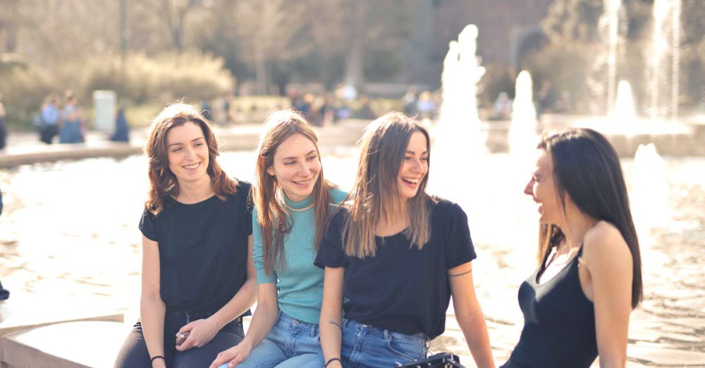 Fountains - Four friends laughing and chatting outdoors by a water fountain on a sunny day.