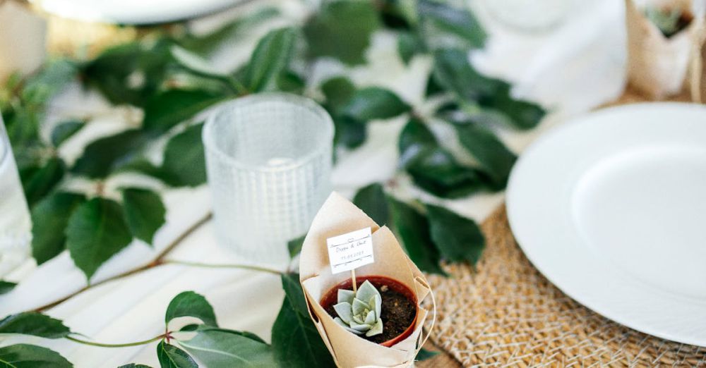 Favors - Sophisticated wedding table arrangement featuring plates, leaves, and succulent favors.