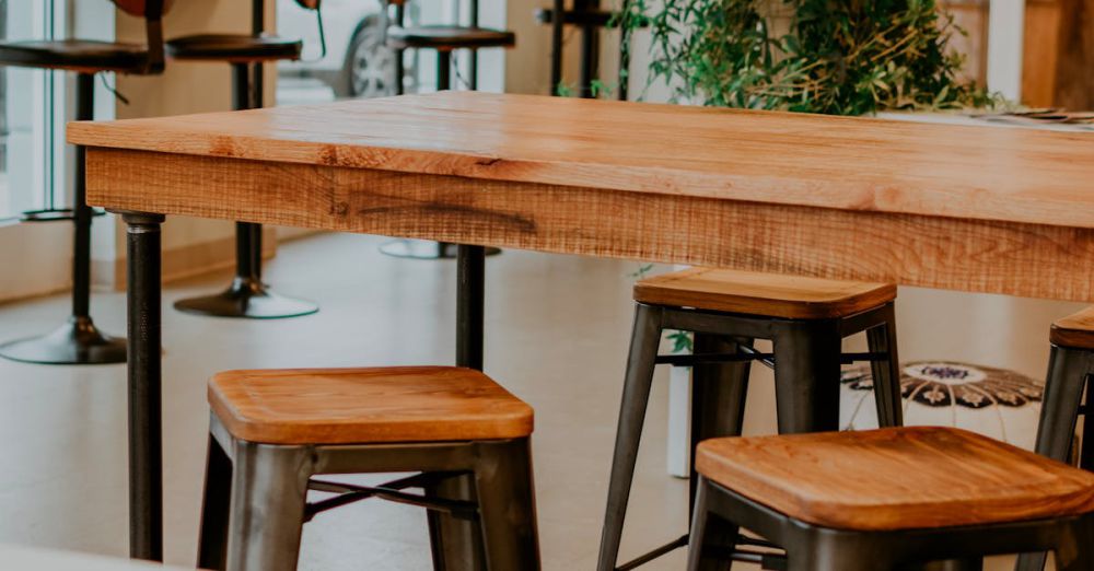 Tables - Contemporary restaurant interior featuring wooden tables and stools with natural light.