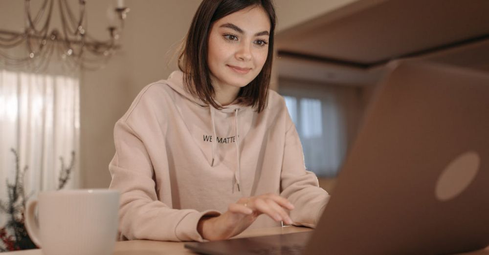 Coffee Boxes - A young woman in a cozy setting using a laptop with a cup of coffee nearby.