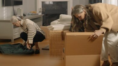 Activity Boxes - Two senior women packing belongings in boxes, preparing for a move in a cozy living room.