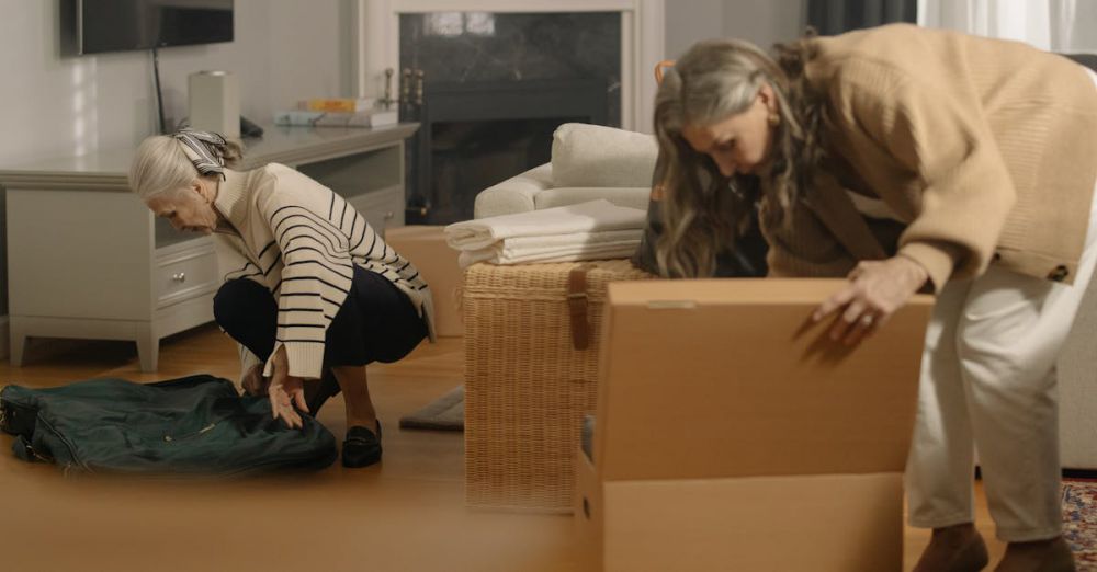 Activity Boxes - Two senior women packing belongings in boxes, preparing for a move in a cozy living room.