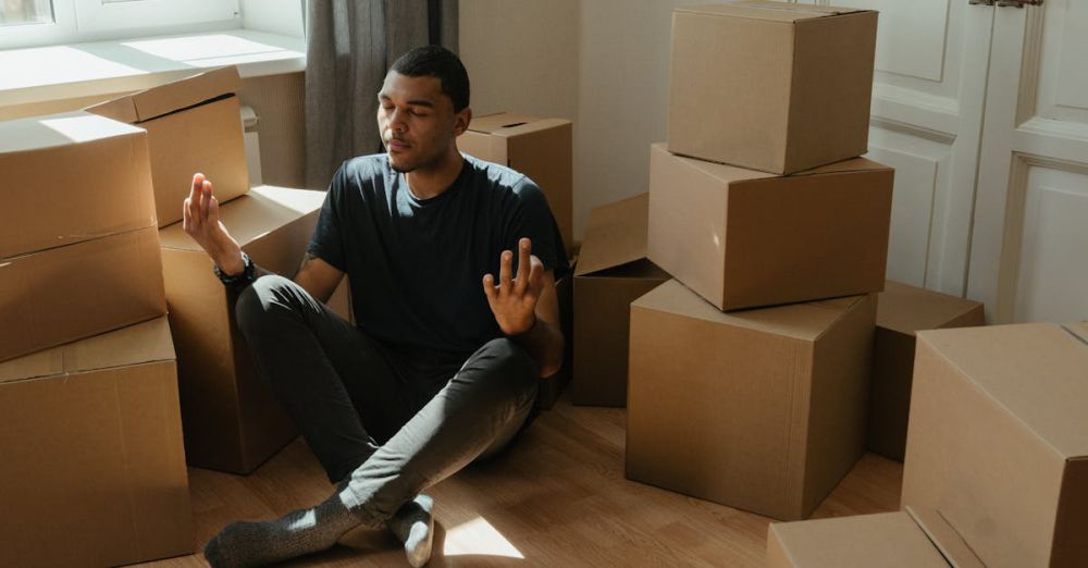 Wellness Boxes - A man practices meditation while surrounded by boxes in a sunlit apartment.