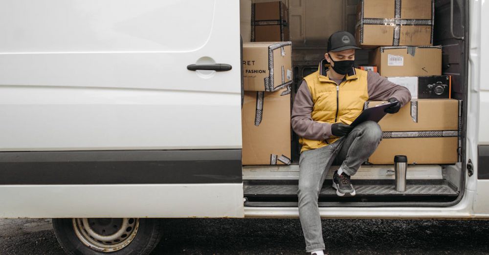 Fashion Boxes - Courier organizing packages and making notes while sitting in a delivery van.