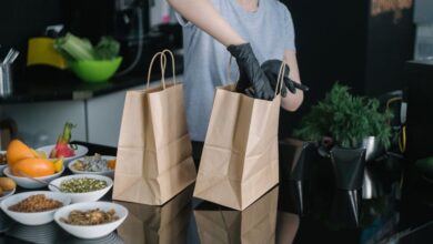 Meal Kits - A person in a kitchen packing food ingredients into paper bags for takeout orders.