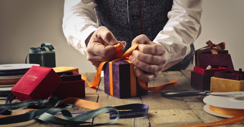 Craft Boxes - A person wraps a gift with orange ribbon on a rustic wooden table, surrounded by boxes.