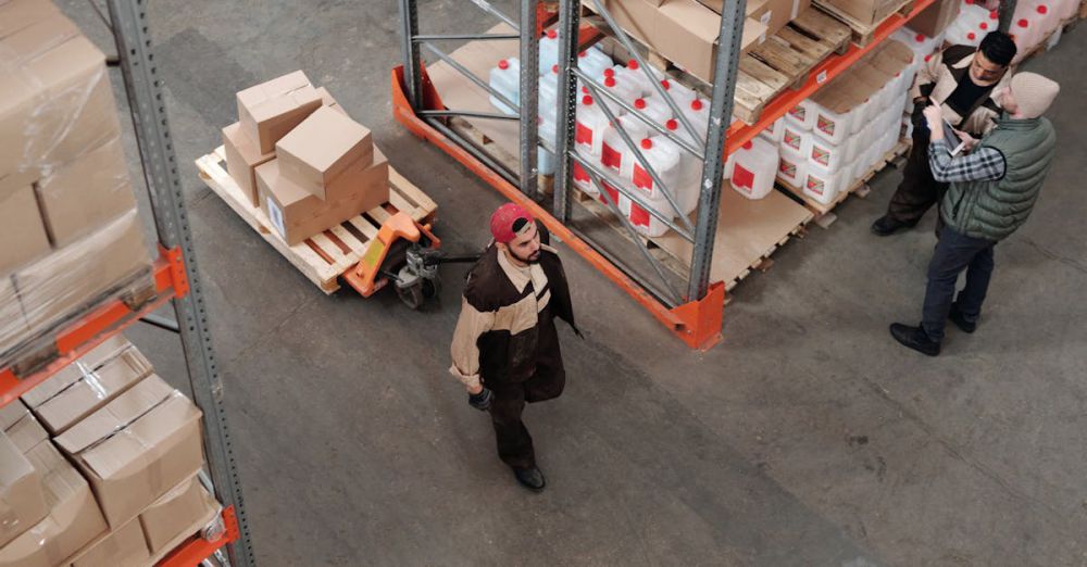 Men’s Boxes - Team working in an industrial warehouse discussing and organizing inventory with pallets.