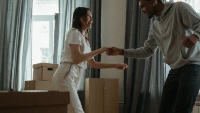 Home Goods Boxes - Happy couple dancing among cardboard boxes in their new home, celebrating a fresh start.