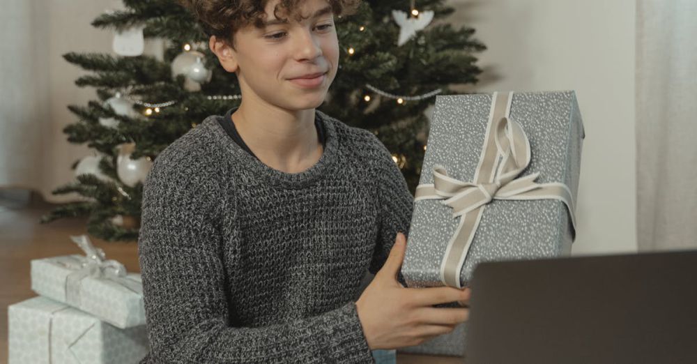 Teens’ Boxes - Teen boy video calling to exchange Christmas gifts at home, showcasing holiday spirit with a decorated tree.