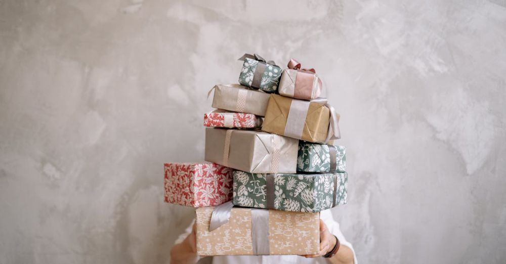 Mystery Boxes - Person hiding behind a tall stack of gift-wrapped boxes against a gray wall, indoors.