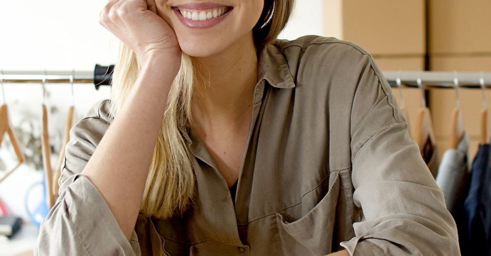 Clothing Boxes - Woman smiling with cardboard boxes in a modern online store setting.