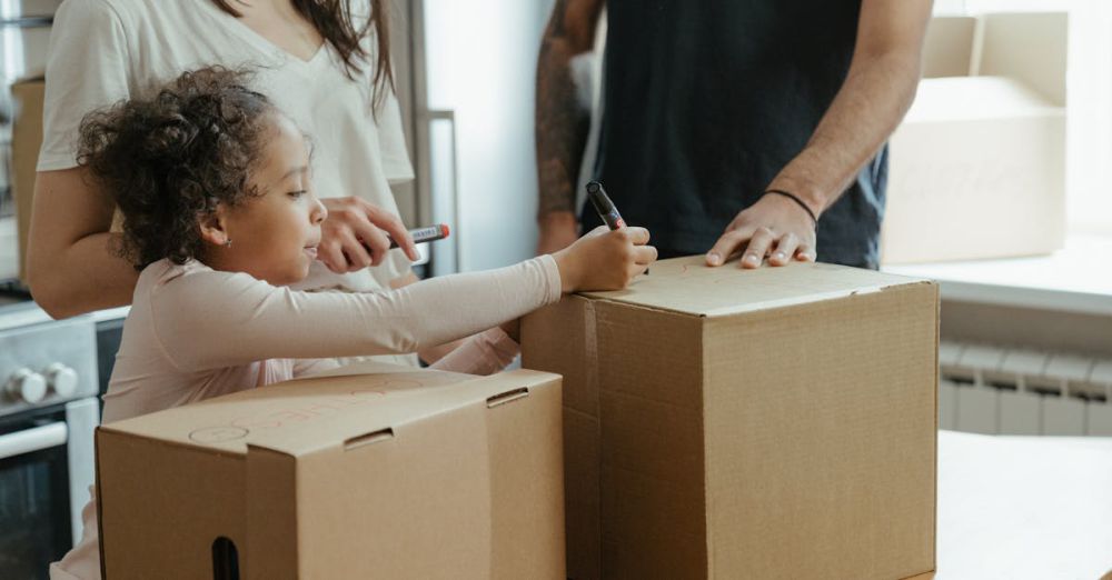 Personalized Boxes - A family labeling moving boxes in their new home, capturing a domestic moment.