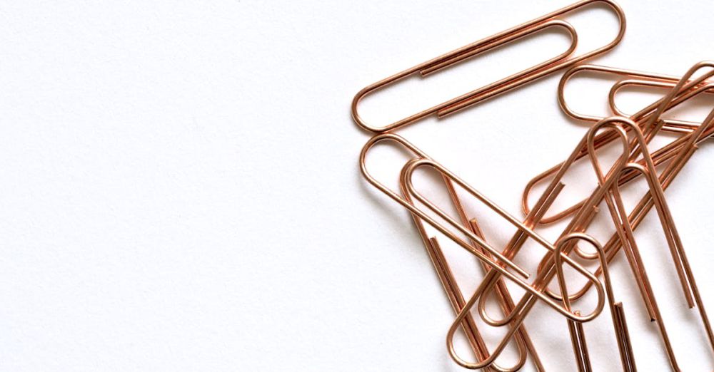 Supplies - Copper paperclips arranged on a white background, highlighting modern office supplies.