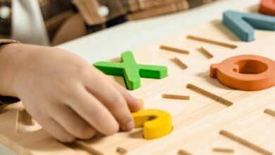 Writing Games - Close-up of a child playing with a colorful alphabet puzzle board.