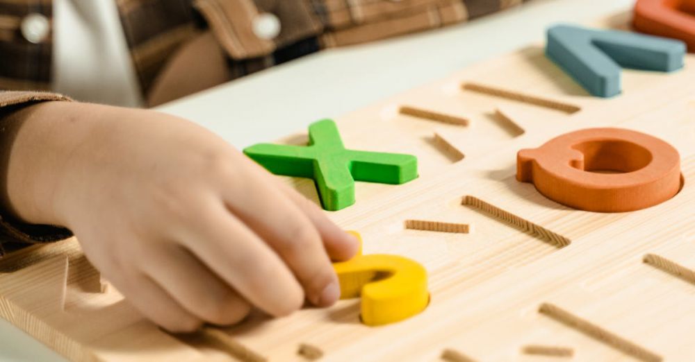 Writing Games - Close-up of a child playing with a colorful alphabet puzzle board.