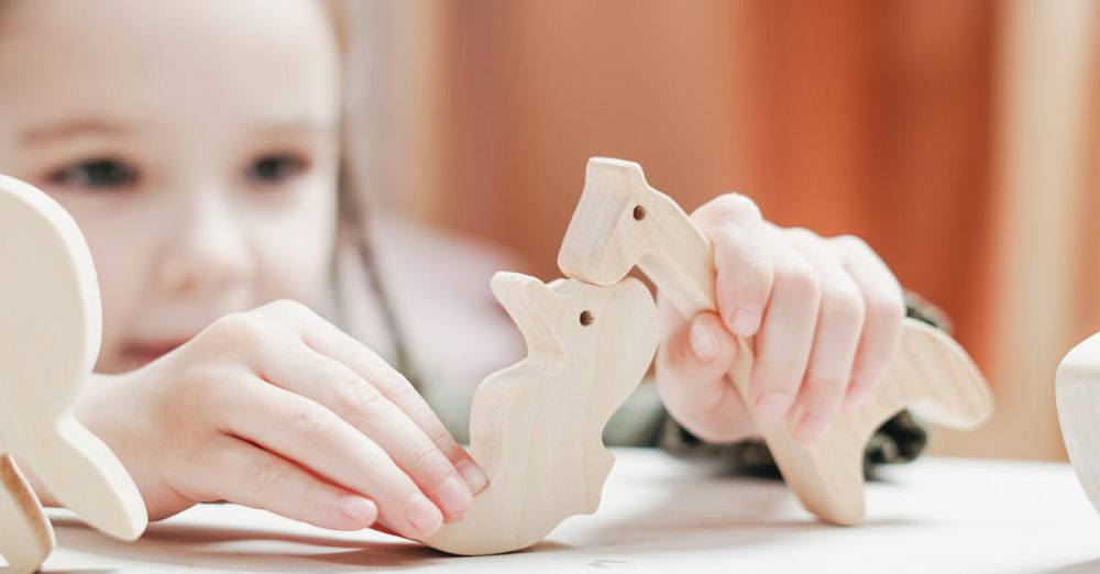 Playsets - Young girl playing creatively with wooden animal toys in an indoor setting.