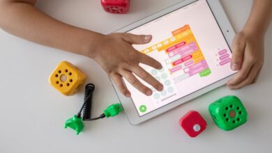 Coding Toys - Child using digital tablet for coding education alongside colorful toy blocks.