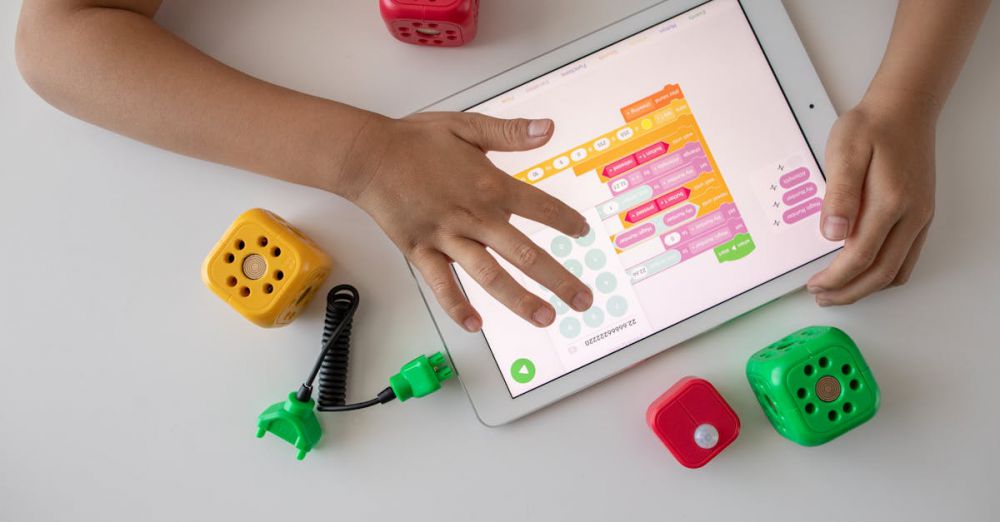 Coding Toys - Child using digital tablet for coding education alongside colorful toy blocks.