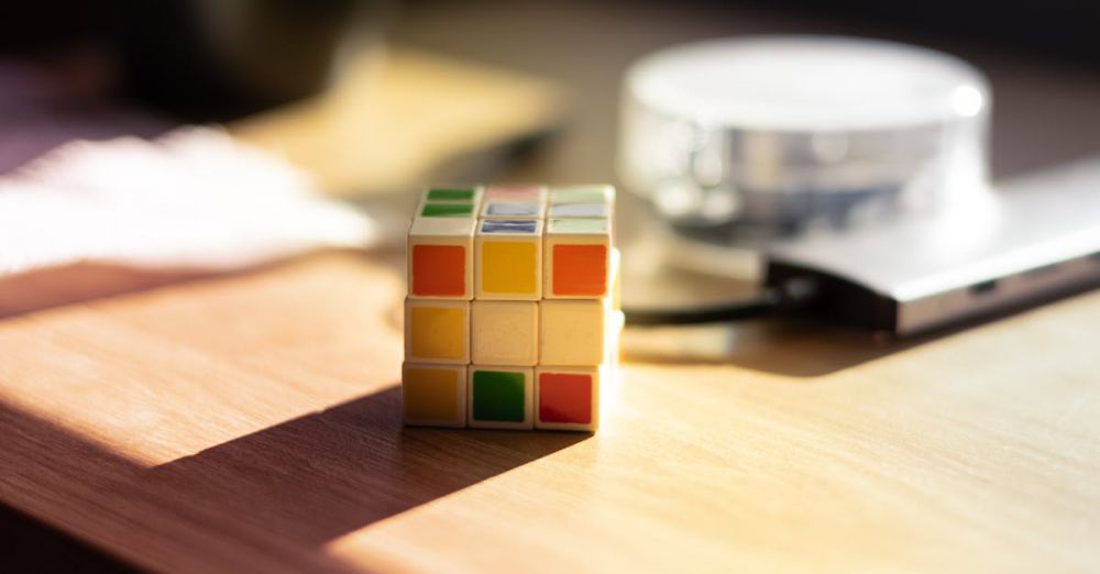 Math Games - A Rubik's Cube sits on a desk, bathed in sunlight, with blurred background elements.