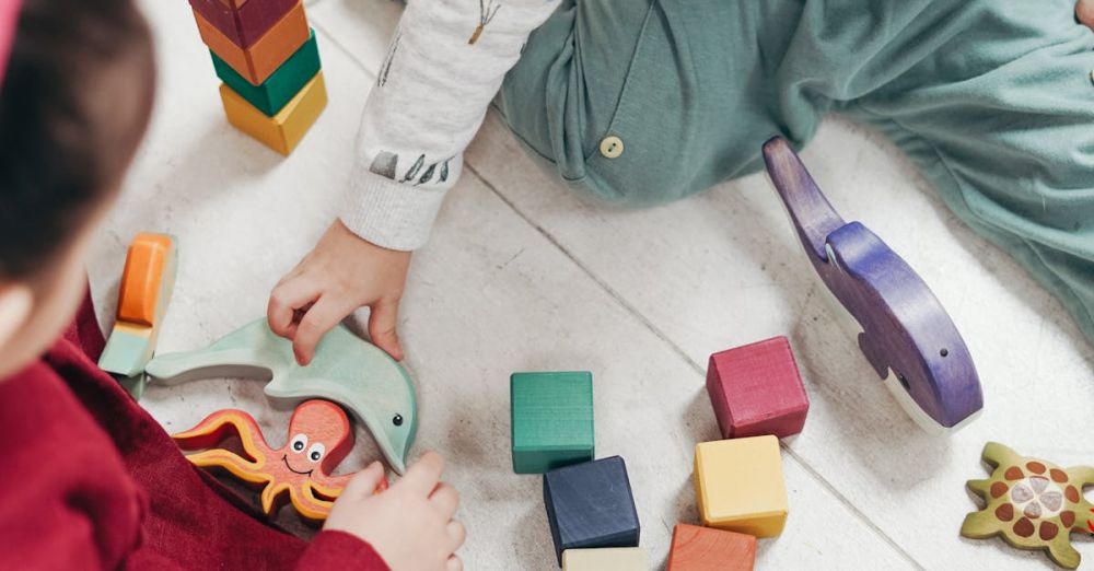 Learning Toys - Two young children playing with colorful wooden blocks indoors, fostering creativity and fun.