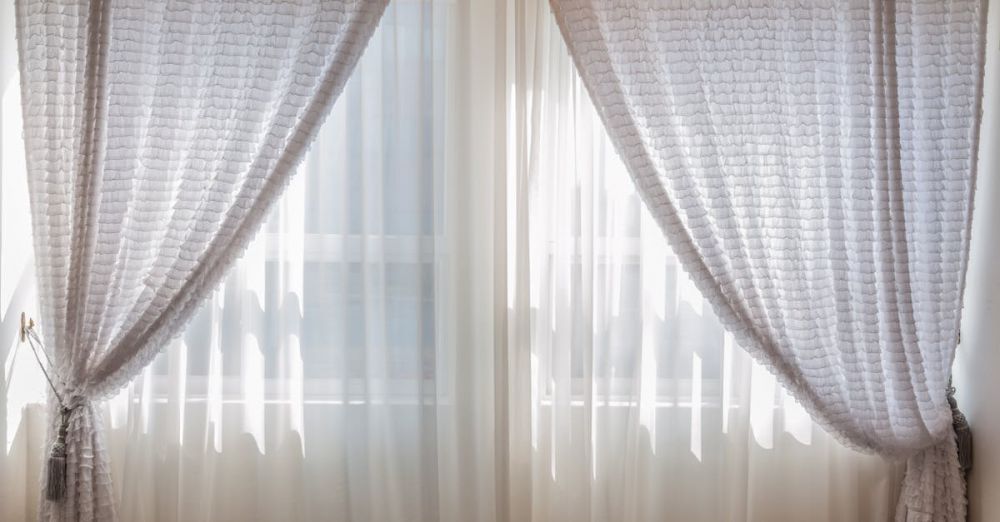 Curtains - Sun shining through elegant white curtains in a cozy, modern interior setting.