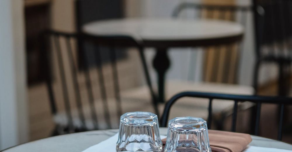 Dining Chairs - Cozy outdoor cafe table with glasses and napkins on a marble top, perfect for evening dining.