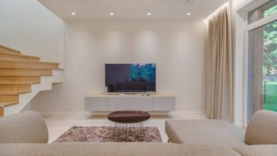 TV Stands - Contemporary living room with stylish sofa, TV, and staircase, offering a cozy interior design setting.