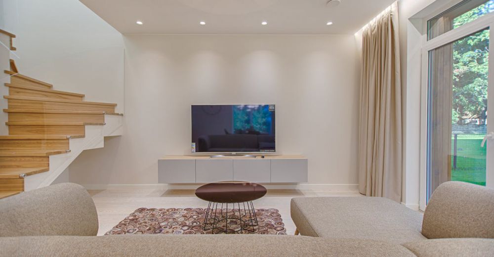 TV Stands - Contemporary living room with stylish sofa, TV, and staircase, offering a cozy interior design setting.