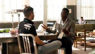 Office Chairs - Two men having a casual discussion in a bright indoor setting, highlighting mentorship.