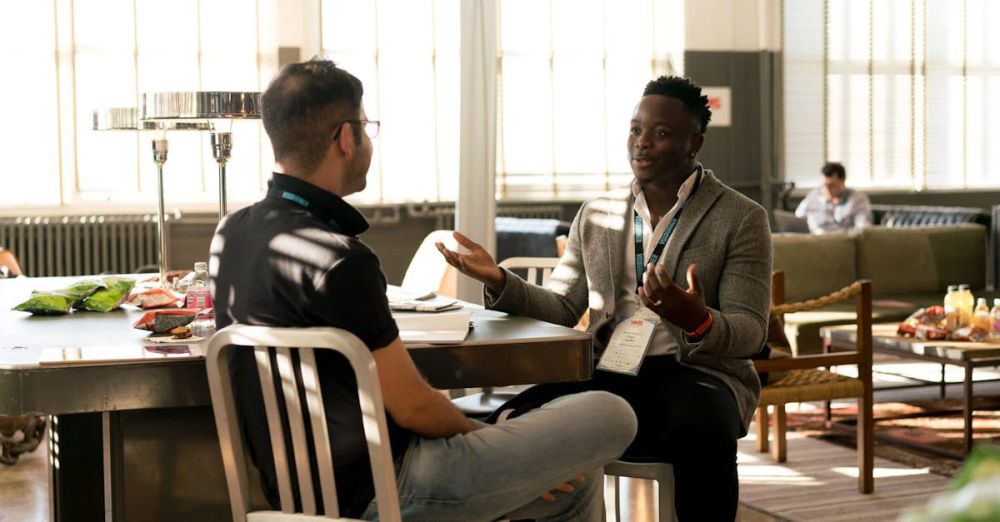 Office Chairs - Two men having a casual discussion in a bright indoor setting, highlighting mentorship.