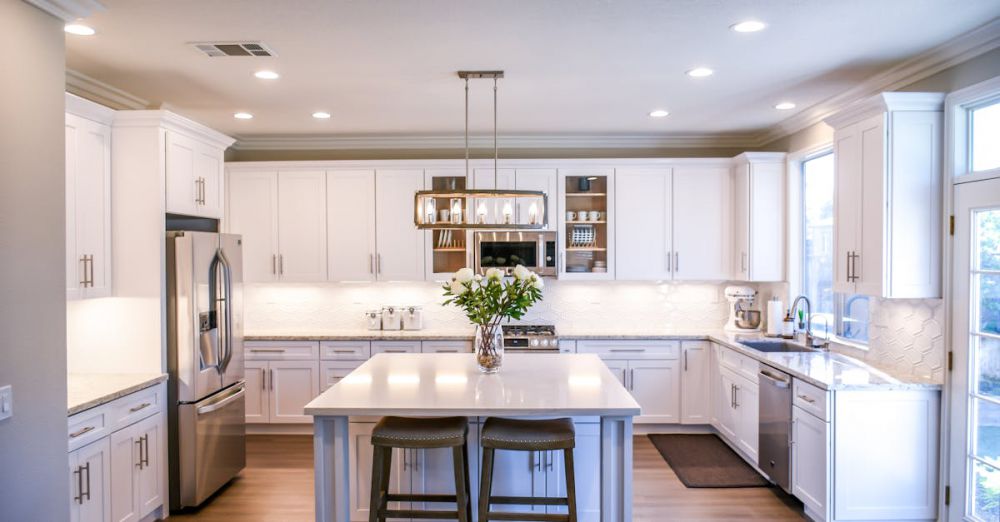 Kitchen Cabinets - Spacious and elegant kitchen featuring white cabinetry, island, and stainless steel appliances.