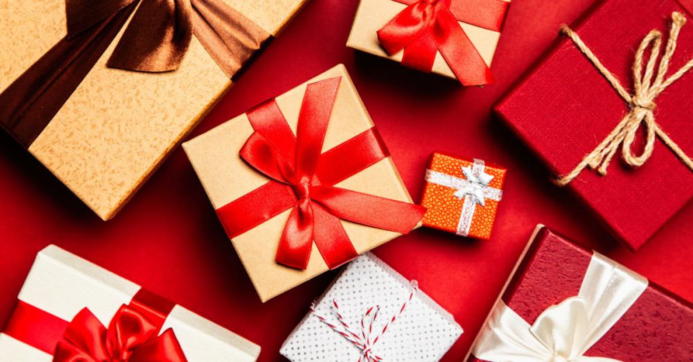 Gifts - Top view of beautifully wrapped holiday gifts with red and brown ribbons on a vibrant red background.