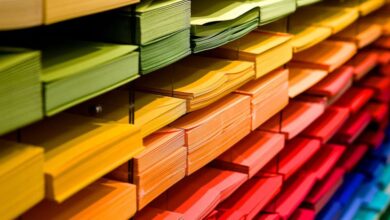 Stationery - Vibrant multicolored paper stacks arranged on shelves in a stationery store.