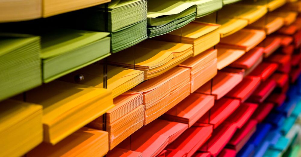 Stationery - Vibrant multicolored paper stacks arranged on shelves in a stationery store.