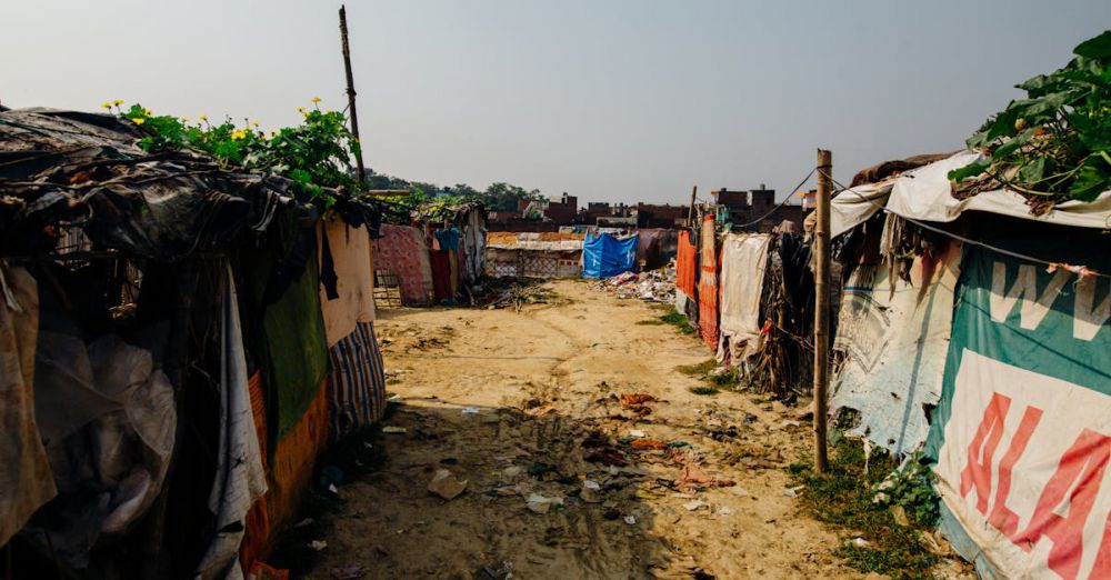 Tarps - A dusty rural pathway flanked by makeshift shelters covered in tarps and signs.