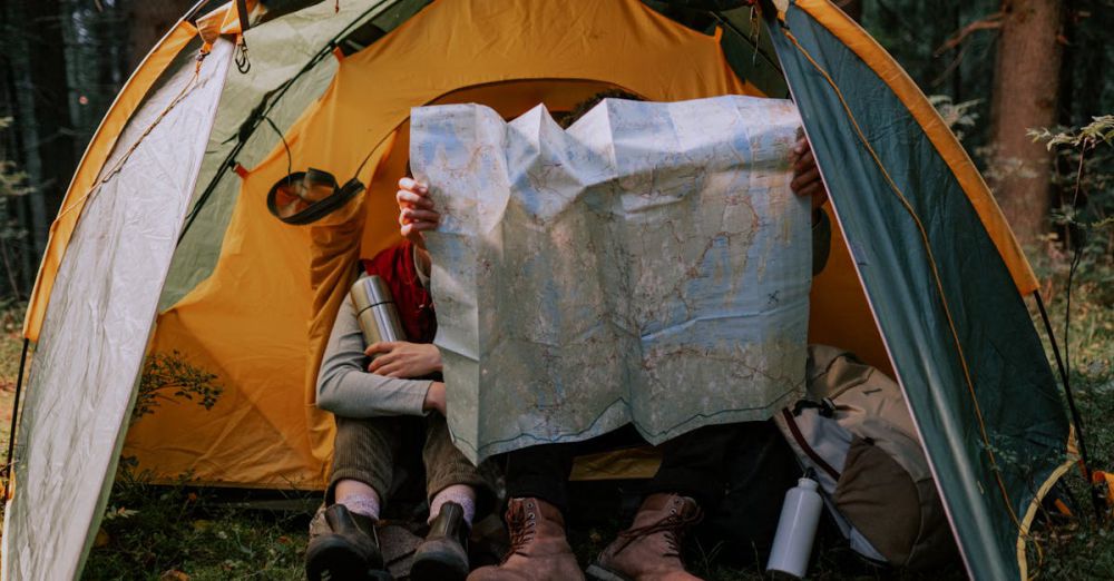 Campfire Accessories - Two people enjoy a camping trip, examining a map inside a tent surrounded by nature.