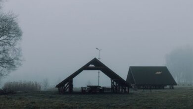 Camping Tables - A foggy morning at a tranquil picnic site with two wooden gazebos amidst a grassy field.